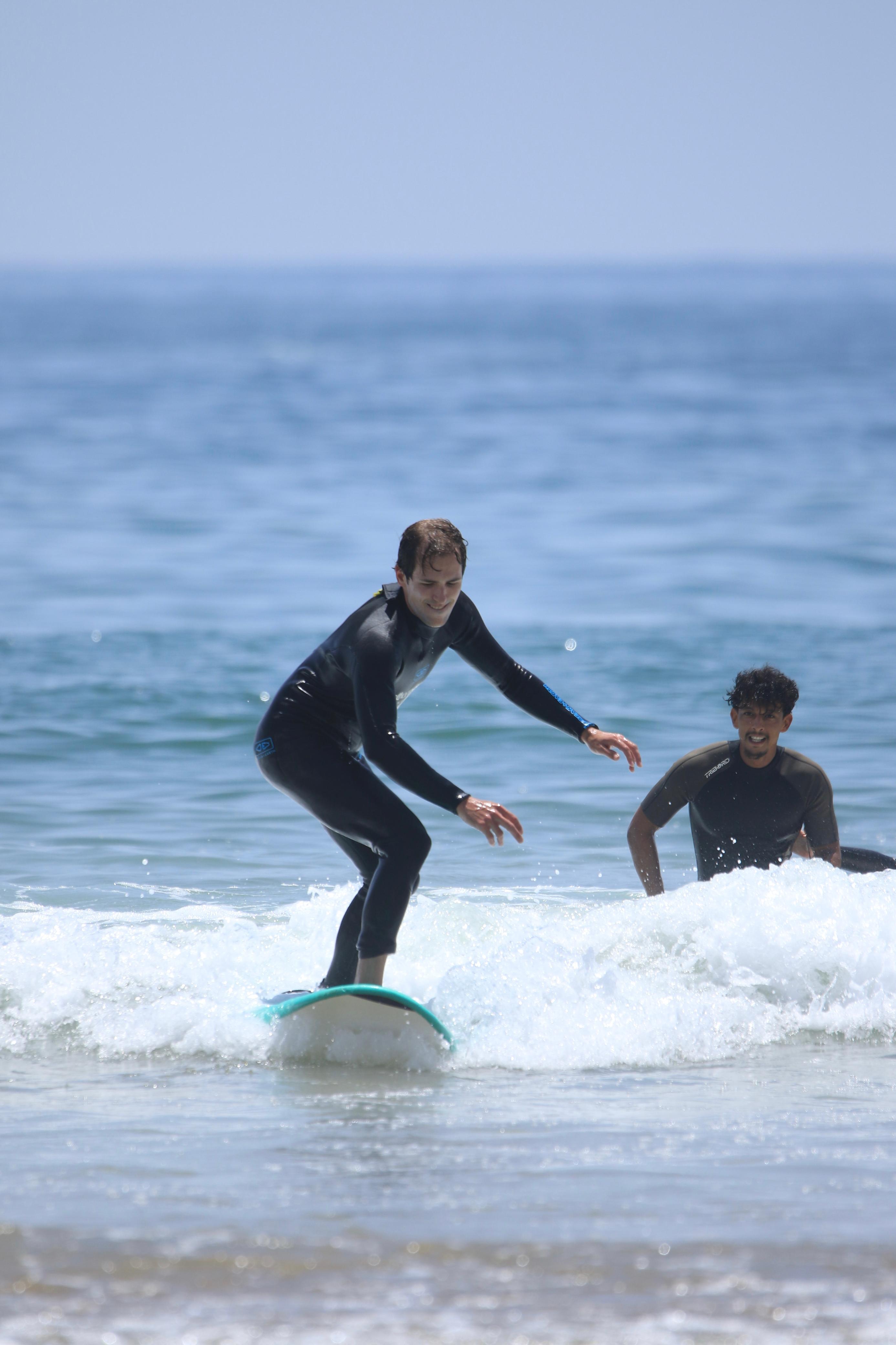 Jamal coaching a surfer individually as they ride a small wave