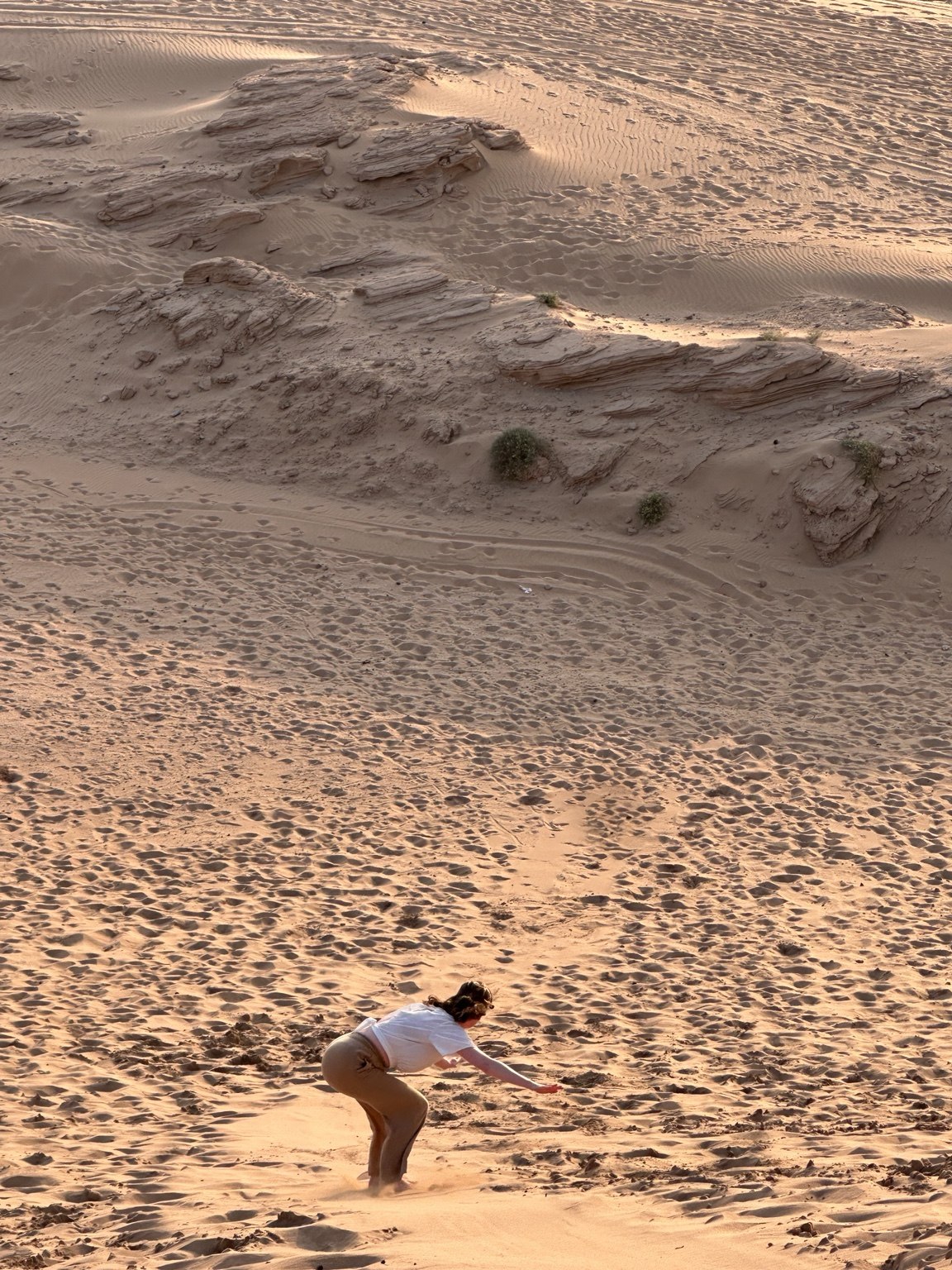 Riding a sandboard down a sandy slope