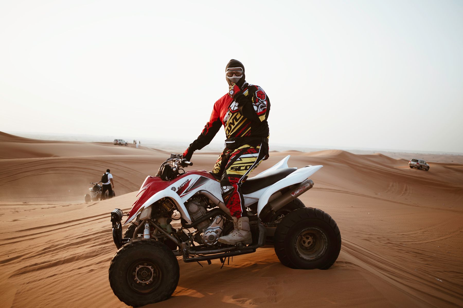 A helmeted quad rider on sandy dunes