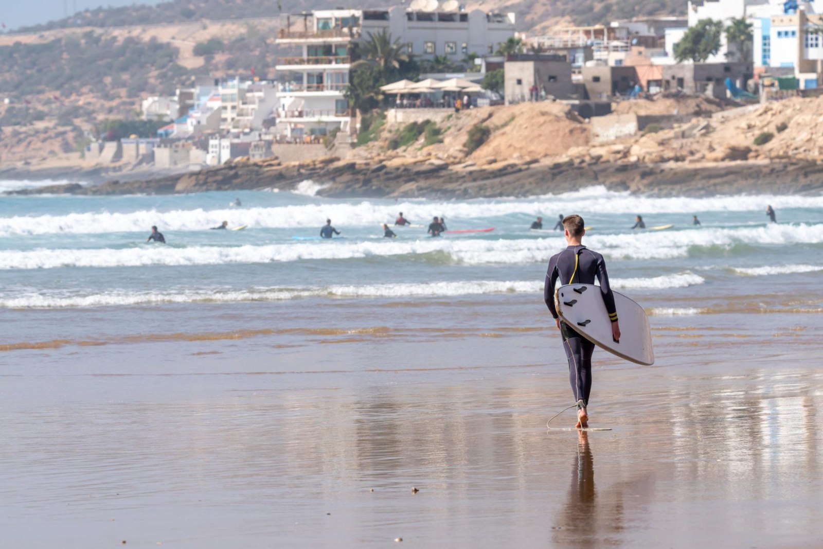 A surfer carrying a board towards the waves